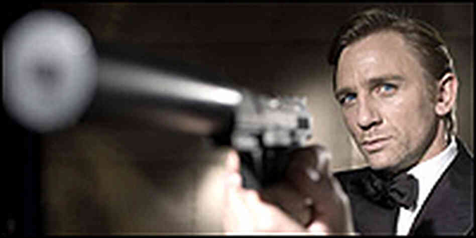 Daniel Craig holds a gun with a silencer that looks huge from the camera angle. Daniel Craig holds a gun with a silencer that looks huge from the camera angle.