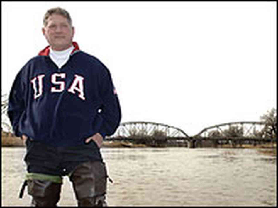 East Grand Forks Mayor Lynn Stauss stand in the Red River in hip waders.