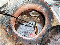 Chapatis are stuck to the side of a tandoor oven — a clay cylinder buried in the ground —  to cook.