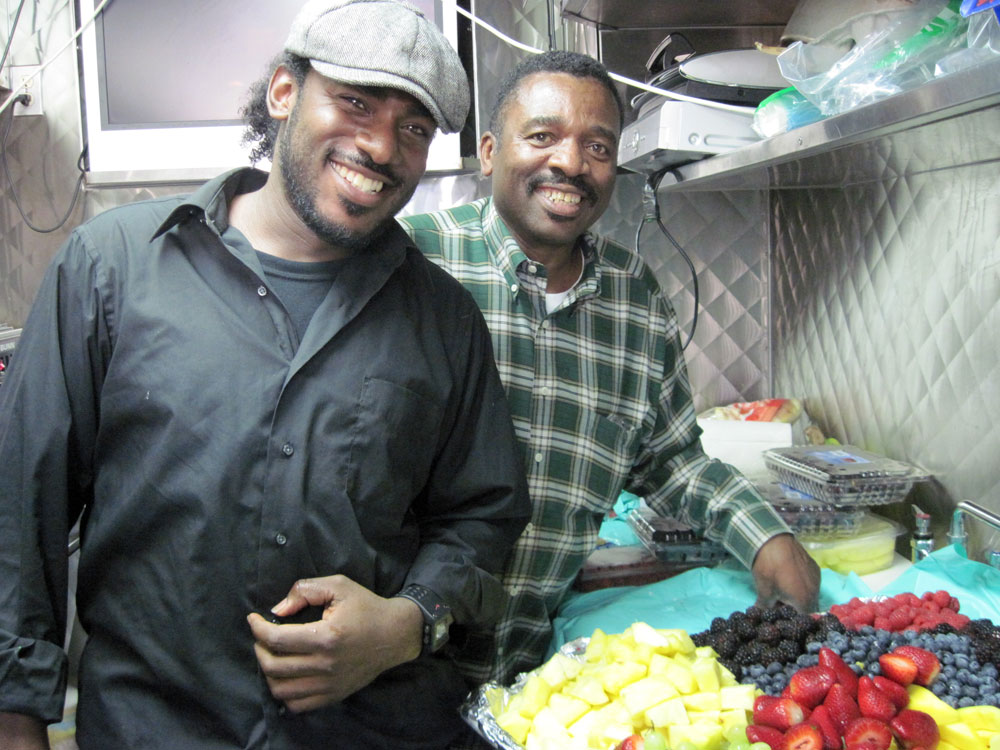 Charlie Scott II (in plaid) has worked in craft service for 15 years; his son, Charlie Scott III, has worked alongside him for the past nine.  Together, they keep everyone on set — from electricians to extras to actors — fed, hydrated and happy. (NPR)