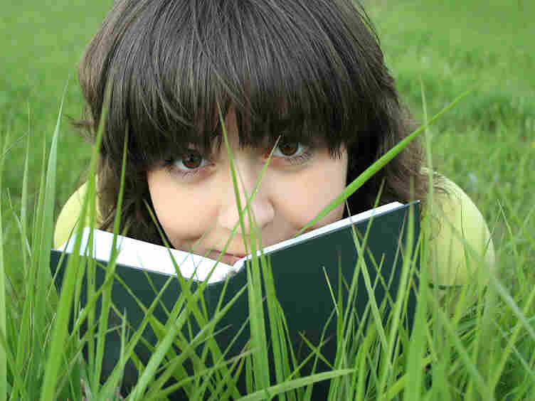 Teen reads book in the grass