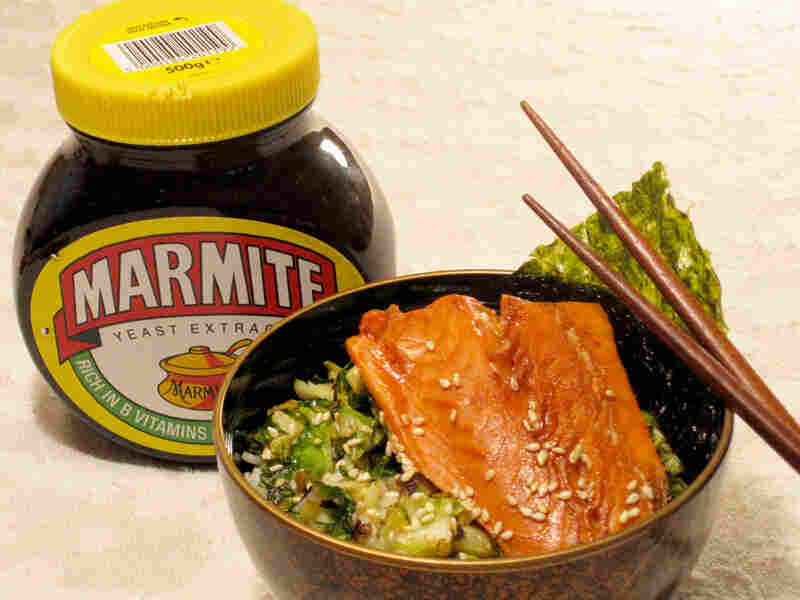 A bowl of rice topped with a salmon filet, sitting next to a jar of Marmite