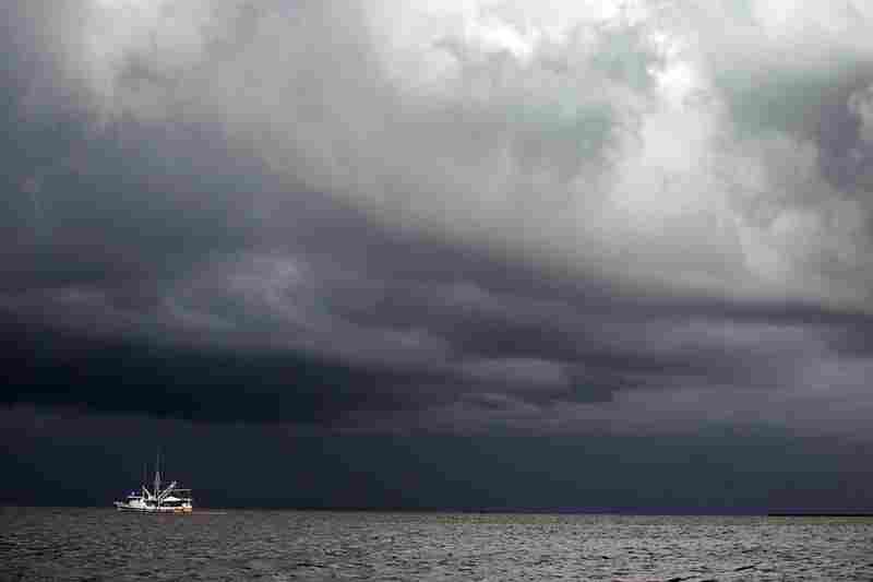 A boat uses a boom and absorbent material to soak up oil in Cat Bay, near Grand Isle, La., on June 28. A tropical storm is expected to hit the Gulf and impede cleanup efforts. 