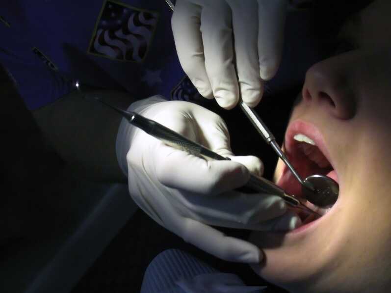 Dentist works on someone's teeth.