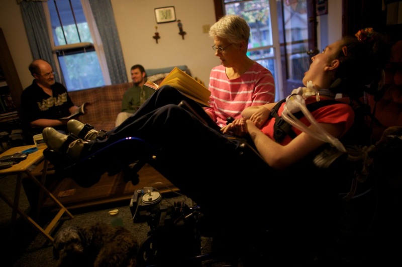Welter's mom, Tamara, reads to her in the family's living room with her father John and brother Brian in Lincoln, Ill. Now, nurses care for Welter 16 hours a day. John and Tamara take over the other eight hours. If they lose the funding for Olivia's care, the Welters will become her round-the-clock caregivers.