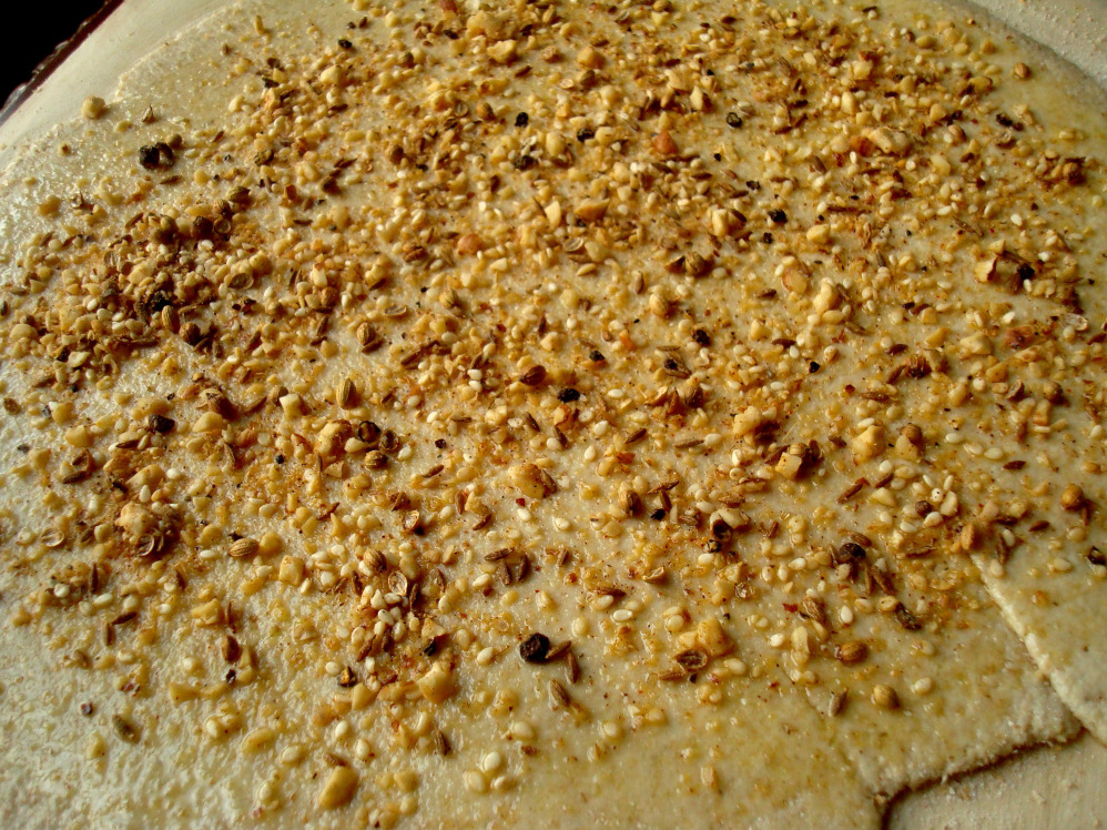 Dukkah can be sprinkled on flatbread before baking, or dipped into with bread or vegetables, among other uses.