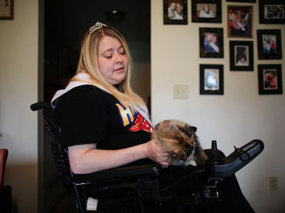 Michelle Fridley, 33, with her cat in her apartment in Canadaigua, N.Y. Ten years ago, on the way to her baby shower, Fridley, then 23, was in a car accident that left her a quadriplegic. This year, she was crowned Miss Wheelchair New York. (John Poole/NPR)