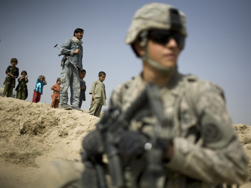 Children and an Afghan policeman look at a U.S. soldier on patrol in Kandahar