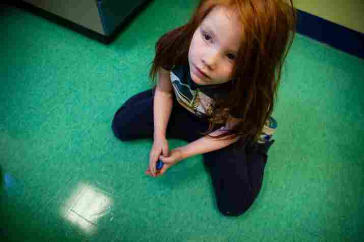 Katie looks up at her mother from the floor of the doctor's office. The symptoms of lead poisoning include behavioral problems, headaches and sleeplessness. But Moore says it's especially hard to detect symptoms in kids with learning disabilities.