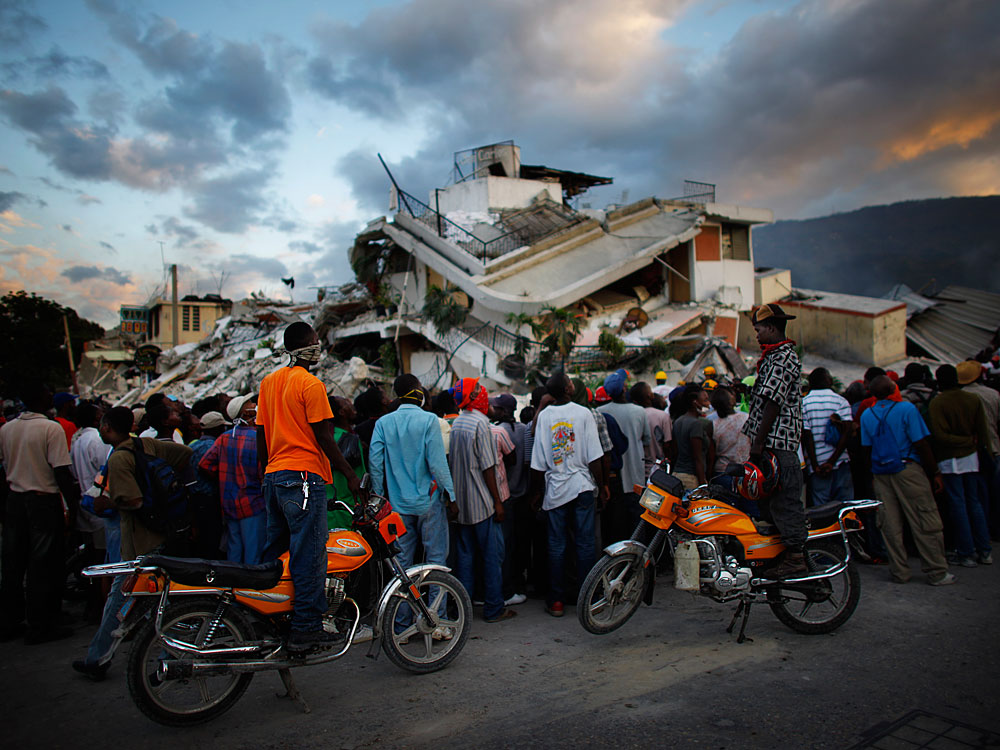 Haitians watch the L.A. County Search and Rescue working at a collapsed building in downtown Port-au-Prince, Jan. 16, 2010.