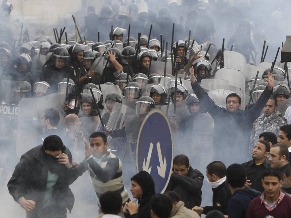 Egyptian anti-government activists clashed with riot police in downtown Cairo on Friday as tear gas and black smoke filled the air. (Ben Curtis/AP)