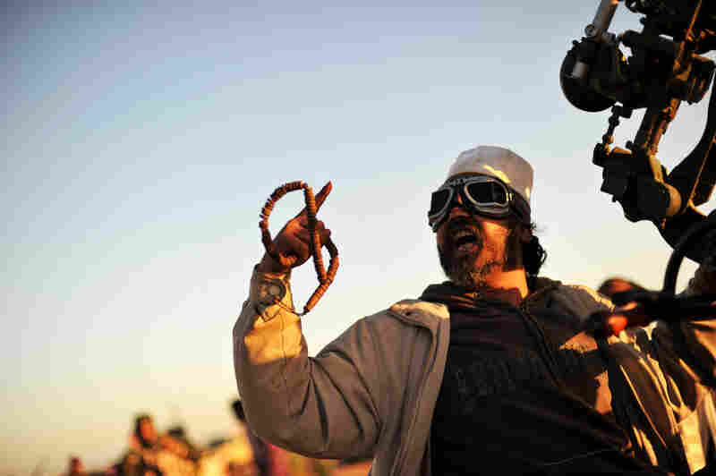 A rebel fighter shouts from his anti-aircraft machine gun position as he sees a fighter jet flying over at a checkpoint on the outskirts of Ras Lanuf on Sunday. 