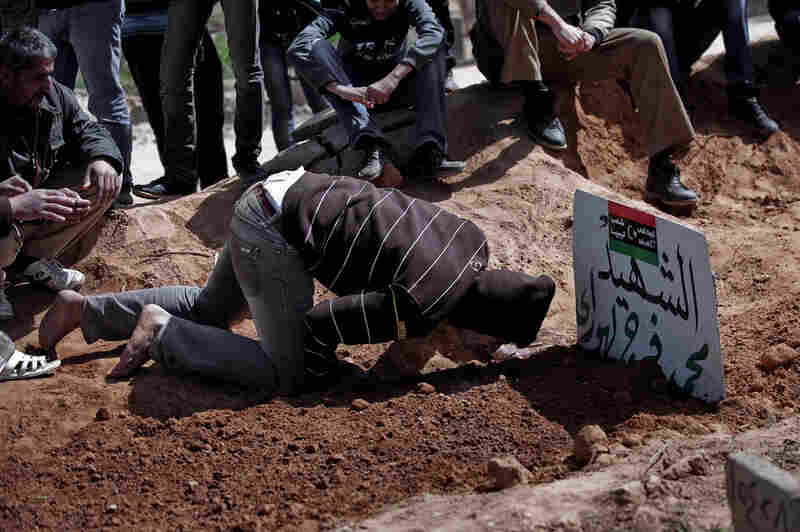 A mourner kneels over the grave of a relative recently killed in a battle between rebel fighters and forces loyal to Libyan leader Moammar Gadhafi for control over the town of Bin Jawad, Libya, on Monday. 