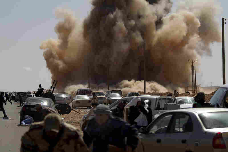 Rebel fighters take cover as a bomb dropped by an air force fighter jet explodes near a checkpoint on the outskirts of the oil town of Ras Lanuf, Libya. 