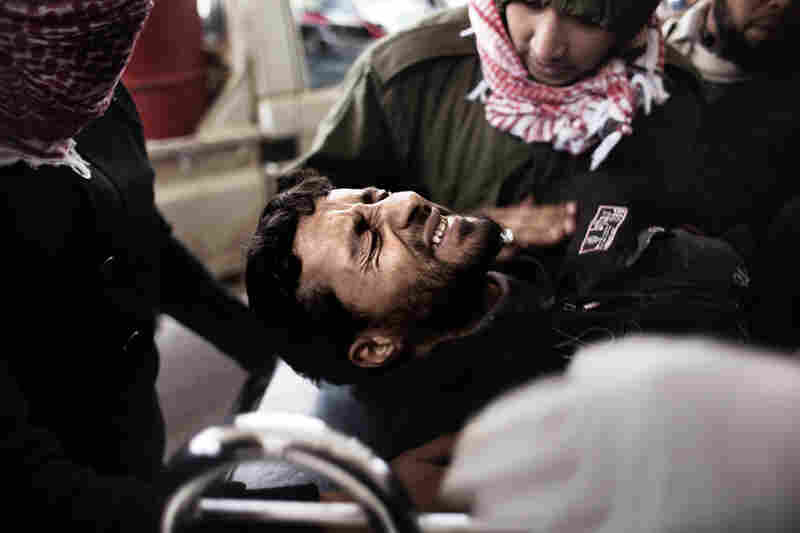 An injured rebel fighter is brought to a hospital in Ras Lanuf on Tuesday. 