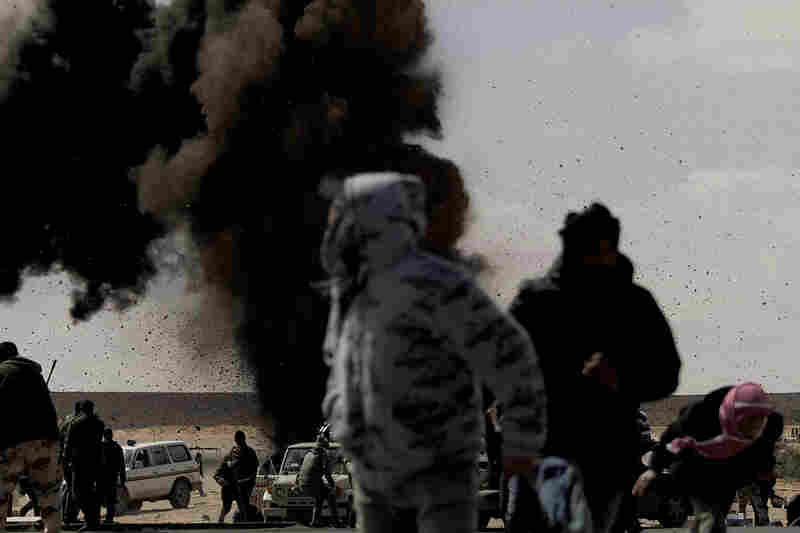 Rebel fighters run for cover as an air force jet drops a bomb on the outskirts of the oil-rich town of Ras Lanuf on Tuesday. 