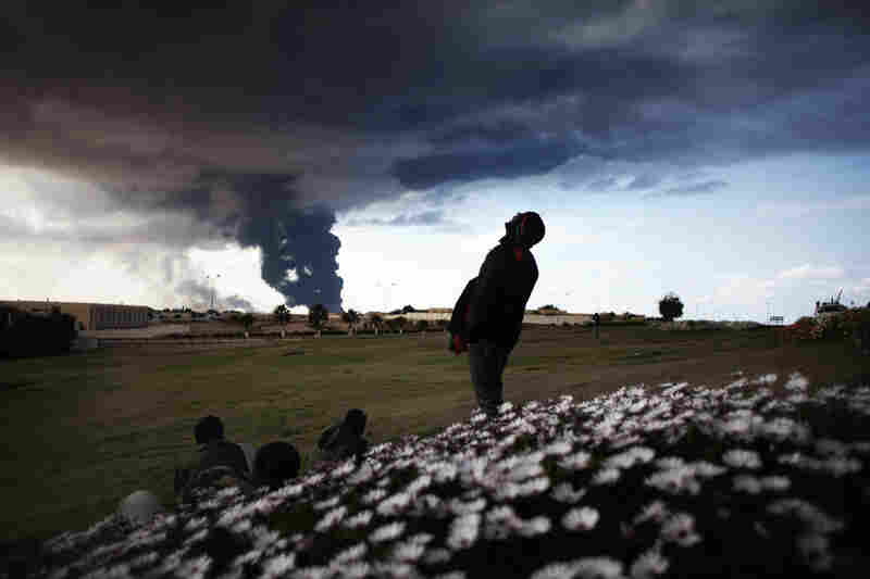 Libyan rebels watch smoke rising from an oil pipe just outside the town of Ras Lanuf, where many anti-regime fighters retreated after artillery and airstrikes from government troops Wednesday. 