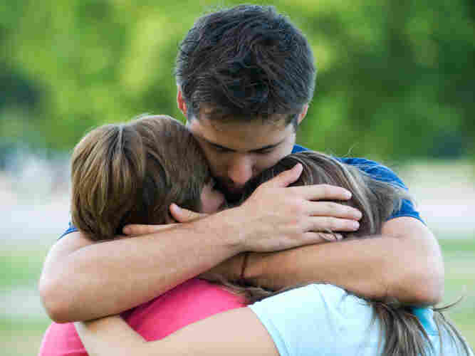 A depressed father hugs his children.
