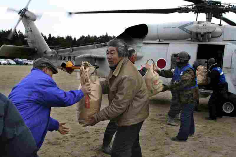 Rescuers and victims carry out bags of food aid from a helicopter in Yamada, northern Japan. 