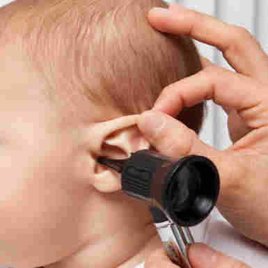 An infant gets an ear checked.