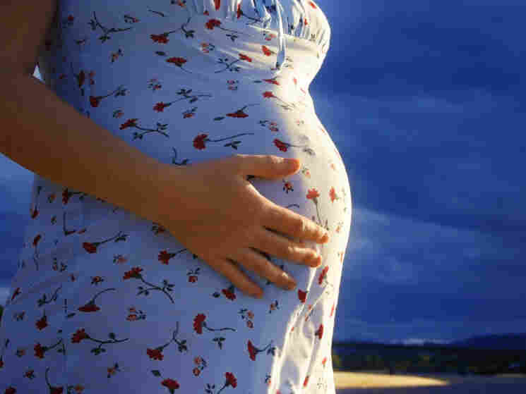 Pregnant woman grasps her belly.