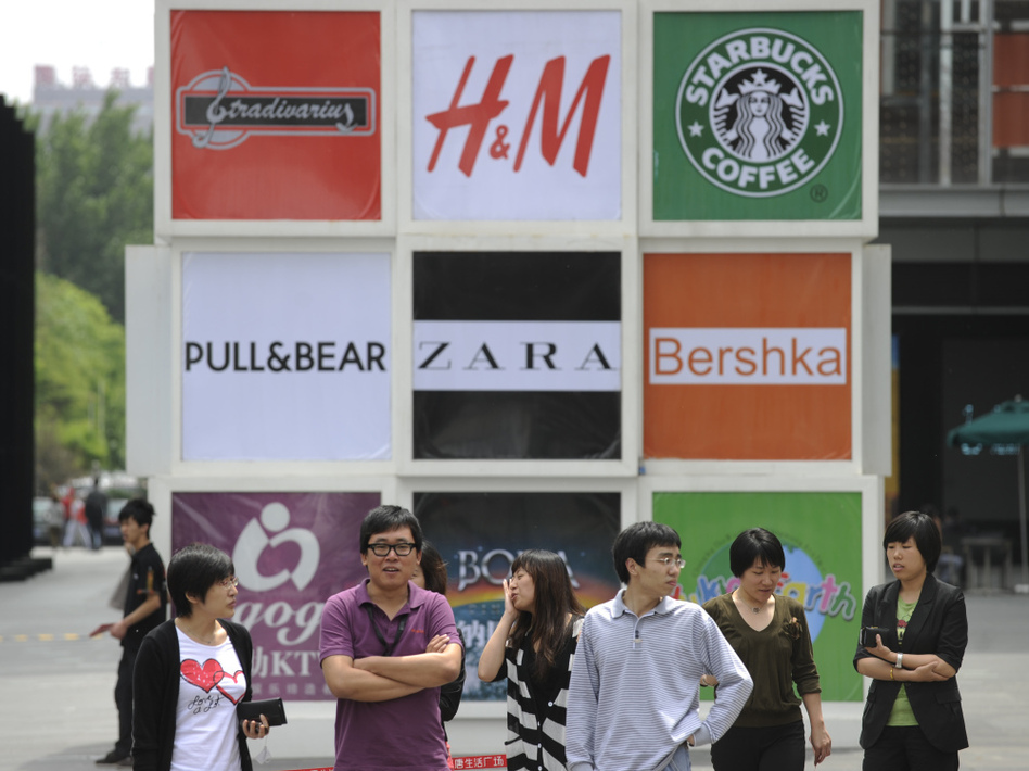 Commuters stand in front of billboards outside a shopping mall in Beijing. Brand logos are a common sight in China — but not for homegrown companies. (Liu Jin/Getty Images)