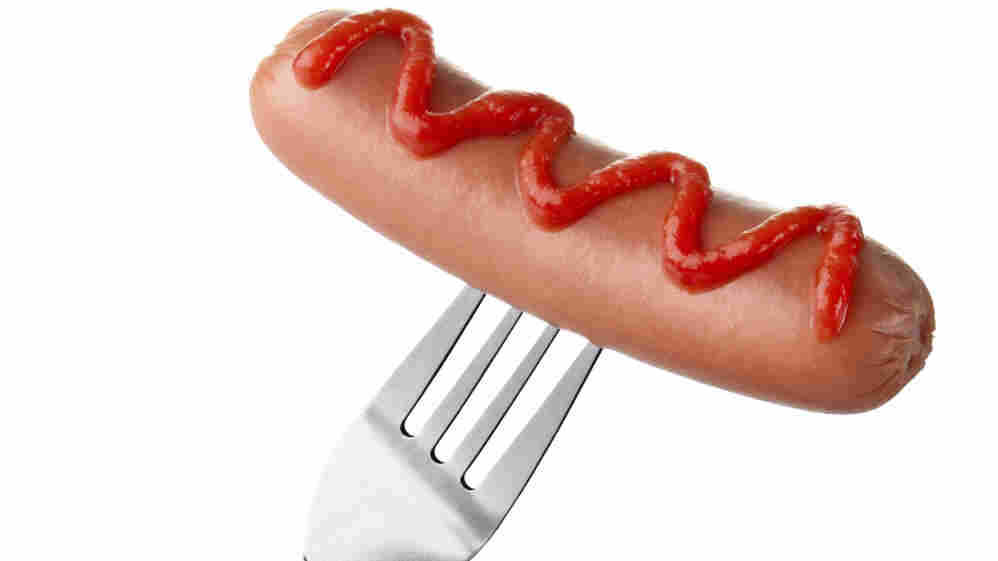 Hot dog on fork with ketchup topping.