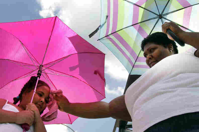 Angela Provis and her daughter Olivia Provis, 6, shield themselves from the afternoon sun while waiting for a bus Thursday in St. Louis. 