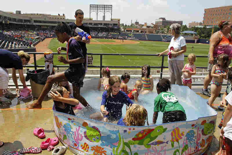 Children keep cool in a swimming pool in right field at Canal Park in Akron, Ohio, on Wednesday. 