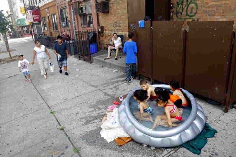 Stephanie Gracia (center) watches as her children and their friends cool off in an inflatable pool outside their apartment Thursday in Brooklyn. 