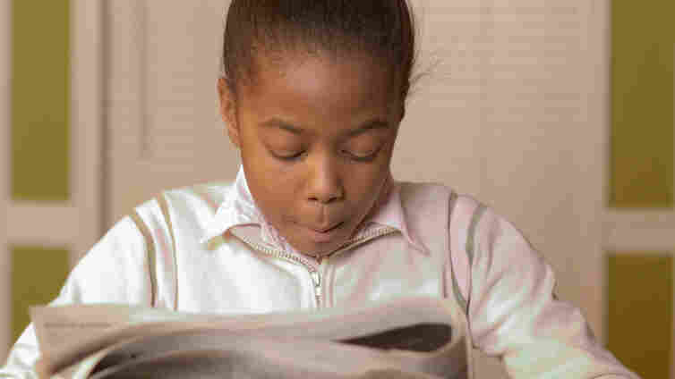 Young girl reading the newspaper.