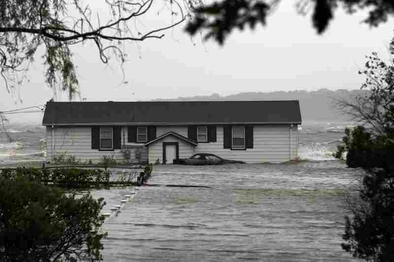 Waves crash around a home Sunday morning in Southampton, N.Y.  