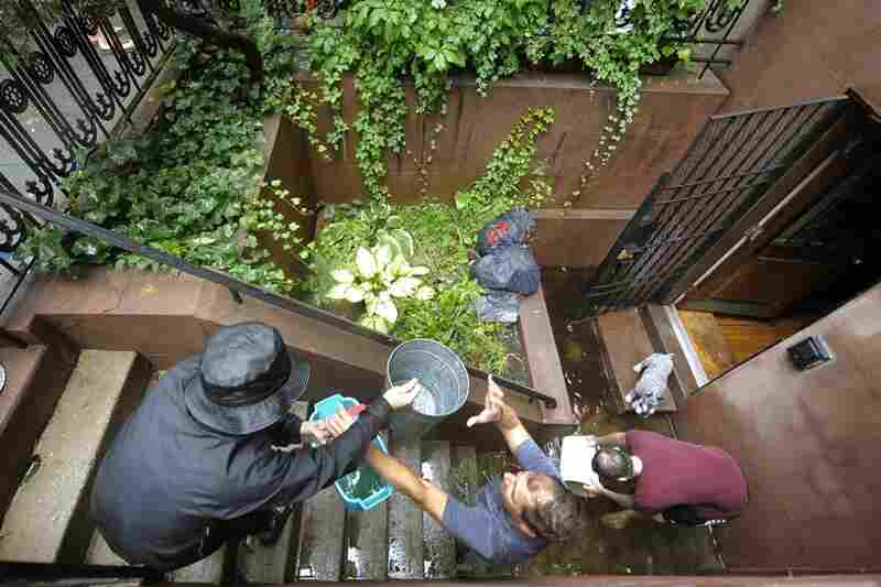 People form a bucket brigade to bail water out of a flooded Chelsea apartment in New York on Sunday. 