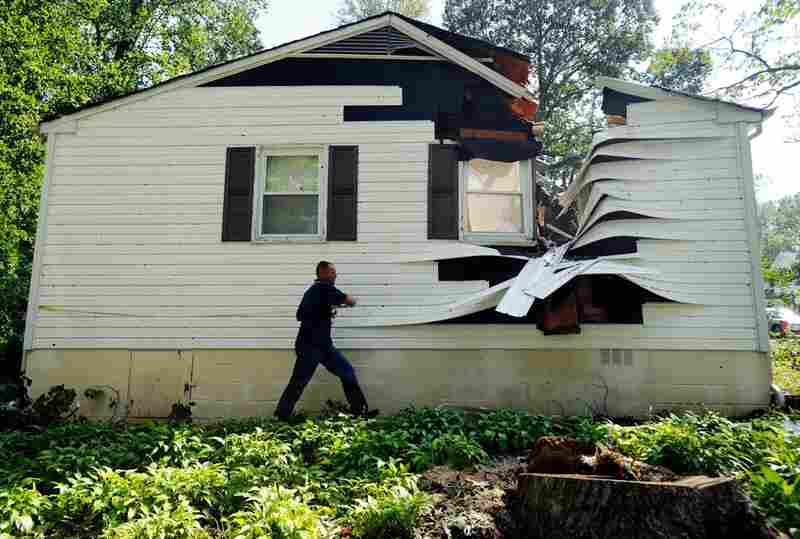 Darrell Tarte surveys damage from a tree at a home hit by the hurricane on Sunday in Port Republic, Md. 