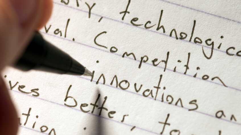 A person writes an essay by hand.