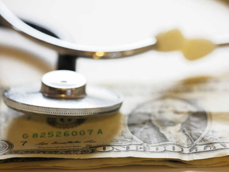 A stethoscope rests on a dollar bill.