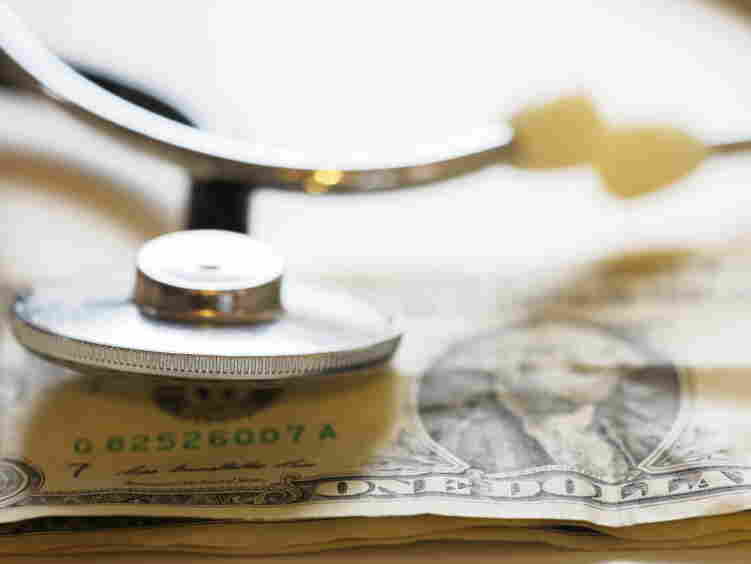 A stethoscope rests on a dollar bill.
