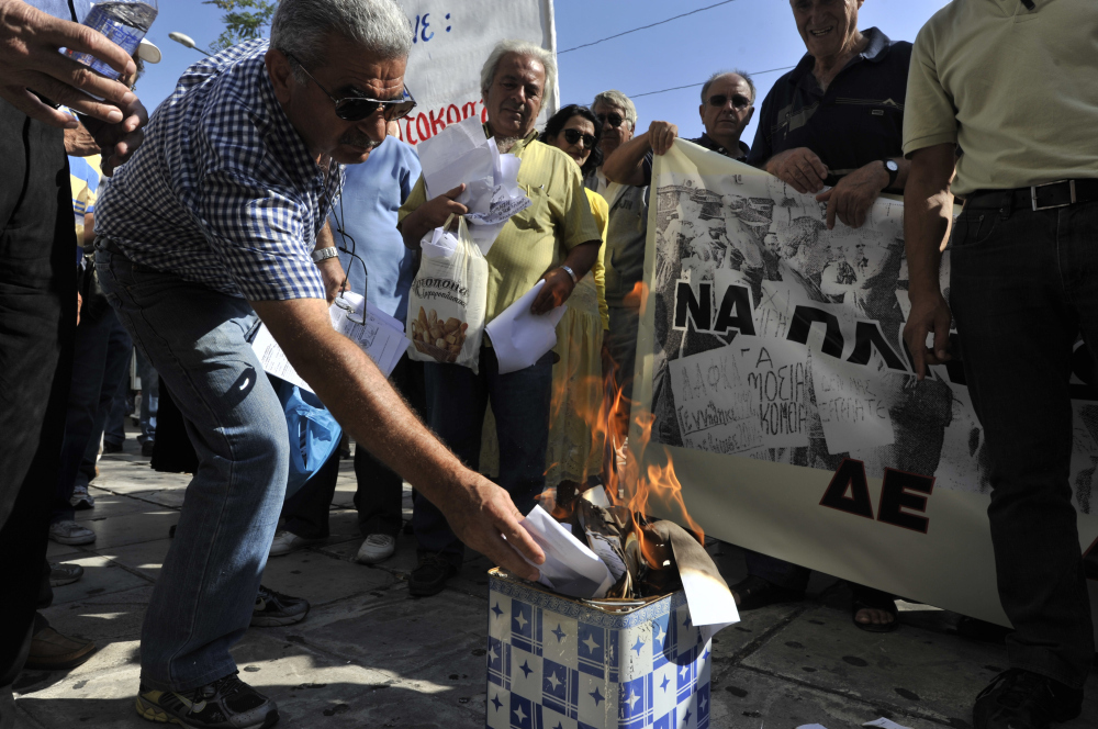 A Greek pensioner burns his emergency tax bill during a protest Wednesday outside the Ministry of Finance in the center of Athens. (AFP/Getty Images)