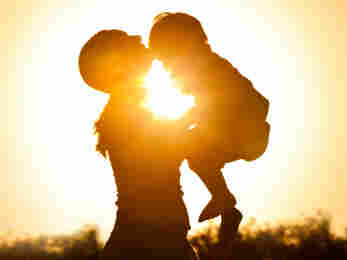 A mother holds her child at sunset.