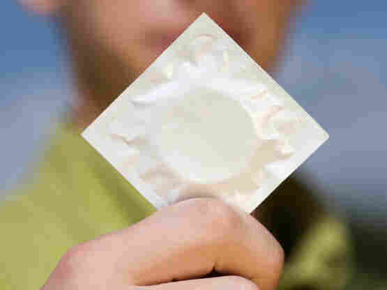 A teenage boy holds a condom.
