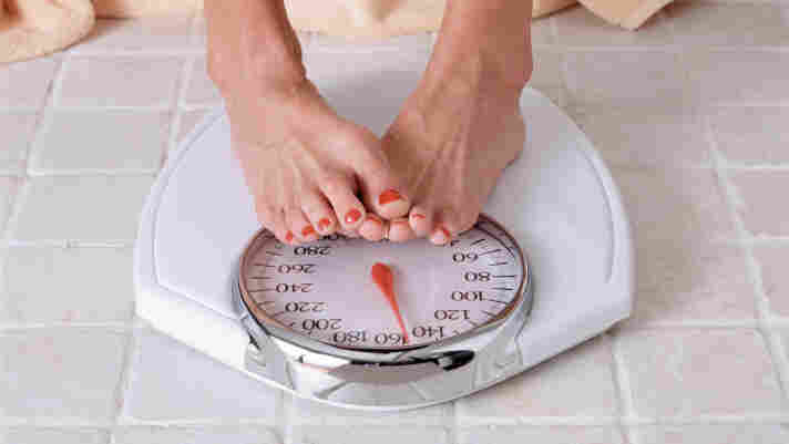 A dieter checks weight on a bathroom scale.