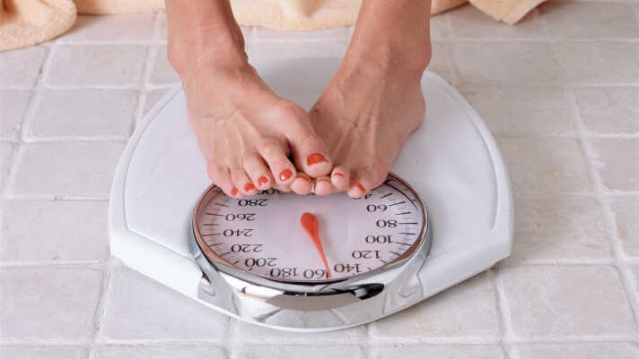 A dieter checks weight on a bathroom scale.