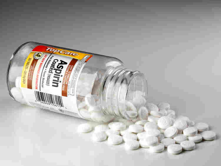 A open bottle of aspirin spills onto a counter.