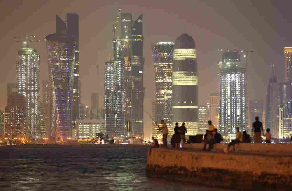 People fish at night across from skyscrapers in Doha, Qatar, in October 2011.