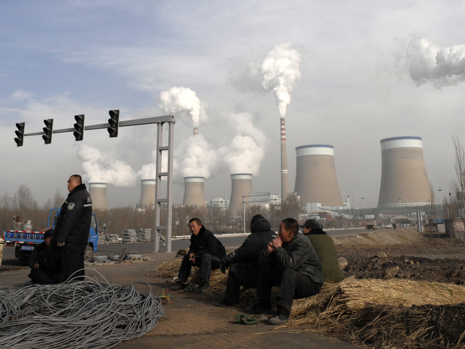Workers take a break in front of the cooling towers of a coal-fired power plant in Dadong, Shanxi province, China. At a House hearing on Tuesday, Nisha Biswal defended USAID's programs in China, saying the money goes to efforts that include reducing harmful emissions from the country's power plants. (Andy Wong/AP)