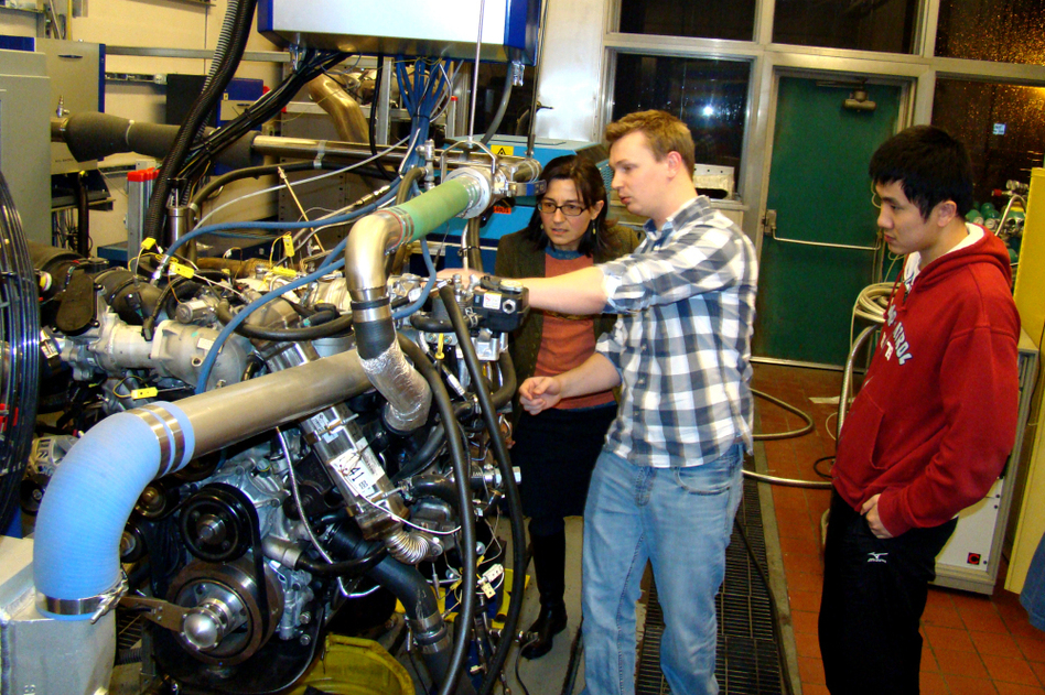 Professor Anna Stefanopoulou (left) examines a V8 internal combustion engine with students Jacob Larimore and Xinfan Lin at the University of Michigan's Automotive Research Center. The researchers model engine performance to improve efficiency. (Courtesy Automotive Research Center)