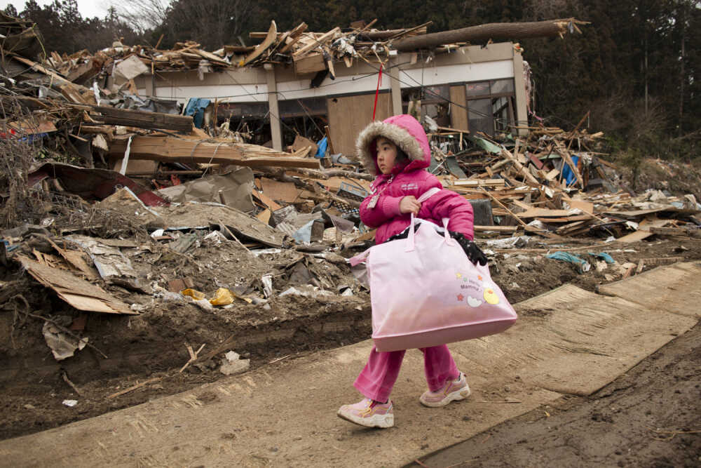Neena Sasaki, 5, carries some of the family belongings from her home that was destroyed after the earthquake and tsunami in Rikuzentakata, Miyagi province, Japan, March 15.