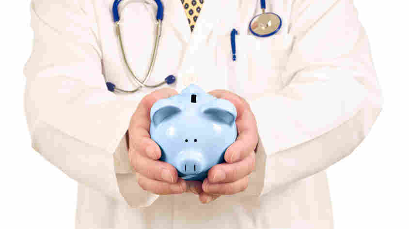 A doctor holds a piggy bank.