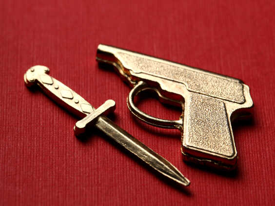 A gun and knife sit on a red fabric field.