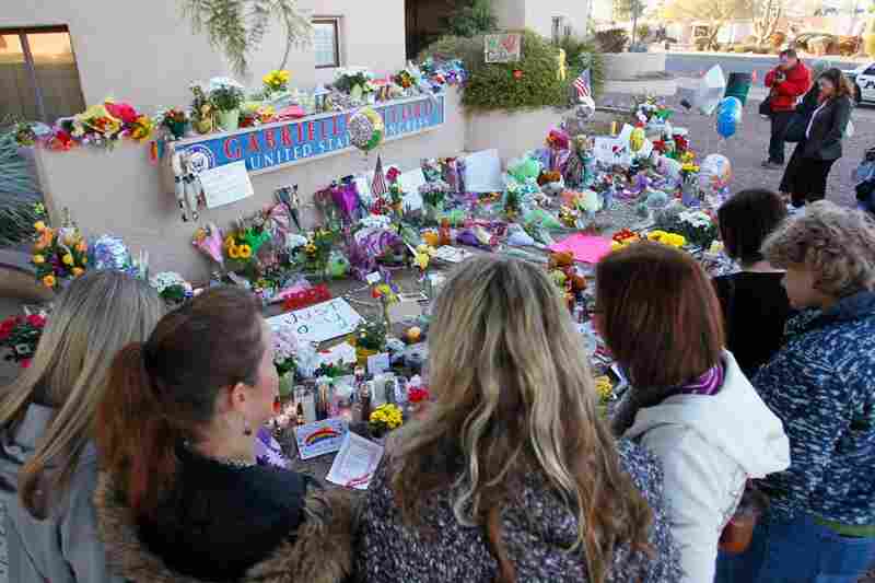 People pay their respects at a makeshift memorial outside Giffords' Tucson office a day after the shooting. 